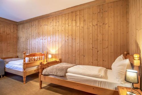 a bedroom with two beds and wooden walls at Villa Noce 2 in Tesero