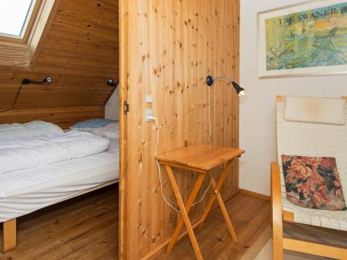 1 dormitorio con 1 cama y pared de madera en Holiday Home Lyngvejen IV, en Rømø Kirkeby