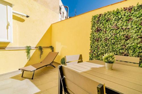eine Terrasse mit einem Tisch und Stühlen sowie einer grünen Wand in der Unterkunft Bright apartment near Casa de Campo by Batuecas in Madrid