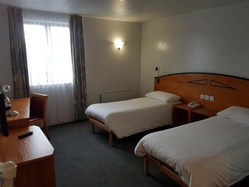 a hotel room with two beds and a window at ibis Cardiff Gate - International Business Park in Cardiff