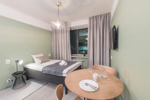 a small room with a table and a bed and a table and chairs at Forenom Aparthotel Jyväskylä in Jyväskylä