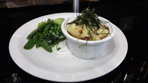 a white plate with a bowl of soup and vegetables at Nevis Bank Inn in Fort William