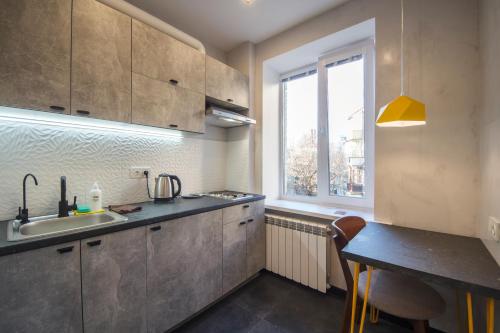 kuchnia ze zlewem, stołem i oknem w obiekcie Modern Apartments on Baseina near Arena City w Kijowie