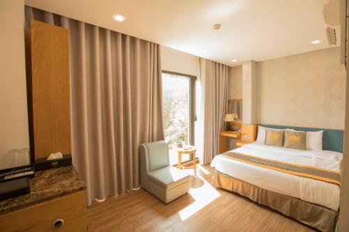 a hotel room with a bed and a chair and a window at The Blue Airport Hotel in Ho Chi Minh City