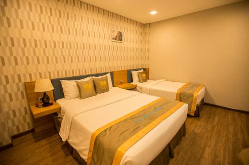 a hotel room with two beds and a lamp at The Blue Airport Hotel in Ho Chi Minh City