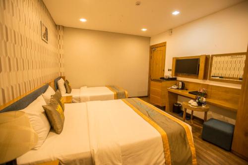 a hotel room with two beds and a desk at The Blue Airport Hotel in Ho Chi Minh City