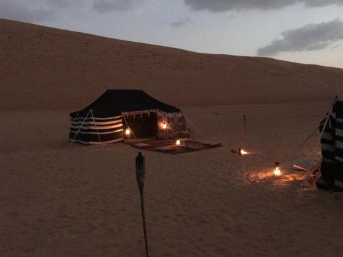 a tent in the desert with lights in the sand at Sultan Private Desert Camp in Bidiyah