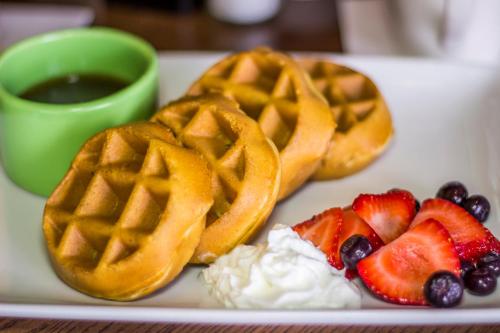 a plate with waffles and fruit and a cup of coffee at Holiday Inn & Suites Across from Universal Orlando by IHG in Orlando