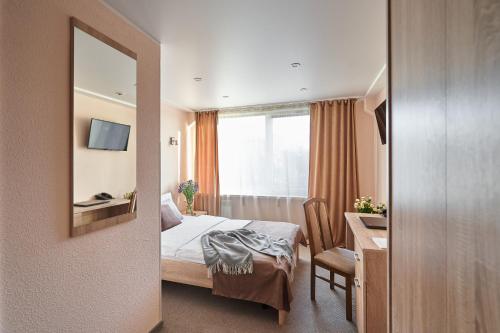 a hotel room with a bed and a desk and a mirror at Hotel Druzhba in Kyiv
