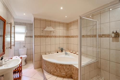 a bathroom with a tub and a toilet and a sink at A Tuscan Villa Guest House in Fish hoek