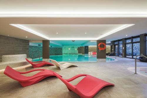 a lobby with three red chairs and a pool at Residence l Hevana - maeva Home in Méribel