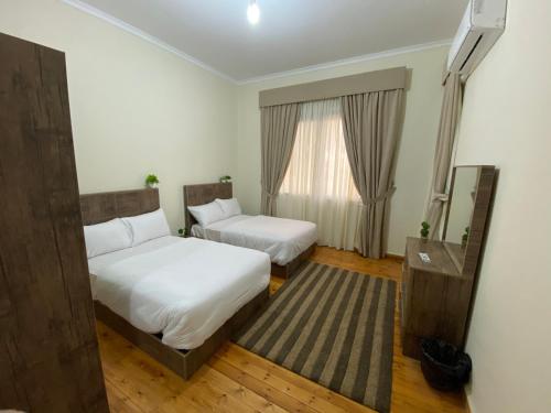 a hotel room with two beds and a window at Brassbell l Downtown l Maspero in Cairo