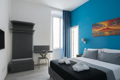 um quarto com paredes azuis e uma cama com toalhas em The Luxury Erica's Apartment em Nápoles