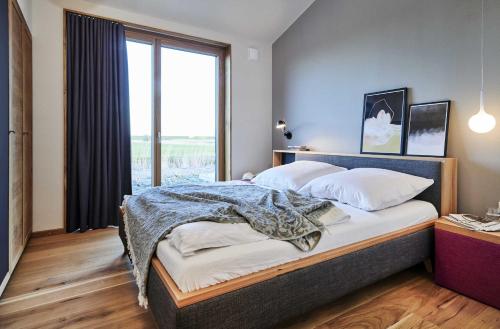 a bedroom with a large bed with a large window at Gud Jard Lodge Nr 13 - Design-Ferienhaus mit exklusiver Ausstattung in Pellworm