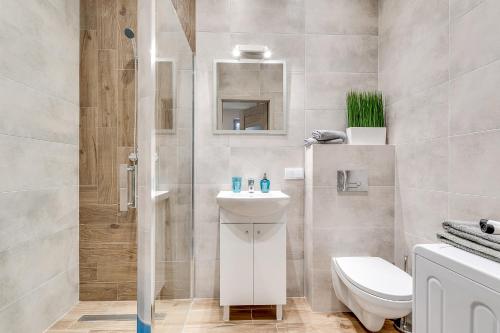 a bathroom with a toilet and a sink and a shower at KATO Apartamenty Słowackiego in Katowice