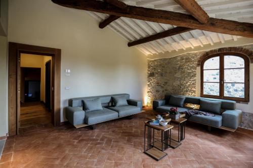 a living room with two blue couches and a stone wall at Castello La Leccia in Castellina in Chianti