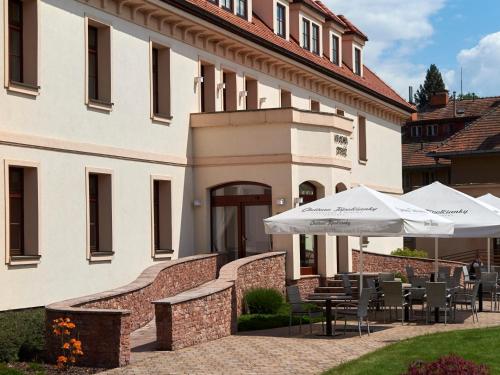 a building with tables and umbrellas in front of it at Hradná stráž Hotel&Apartments s privátnym wellness in Topoľčianky