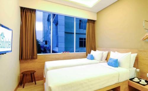 a hotel room with two beds and a window at Desatu Hotel in Medan