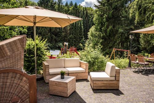 eine Terrasse mit 2 Stühlen und einem Sonnenschirm in der Unterkunft Bielefelder Berghotel zum Stillen Frieden in Bielefeld