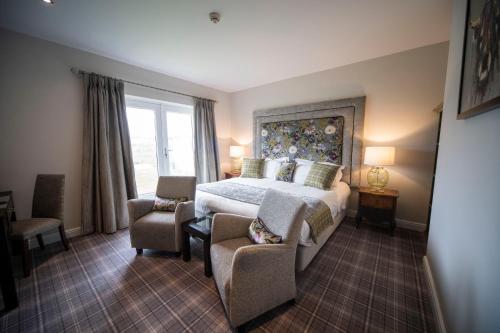 a bedroom with a bed and chairs and a window at Peak Edge Hotel in Chesterfield