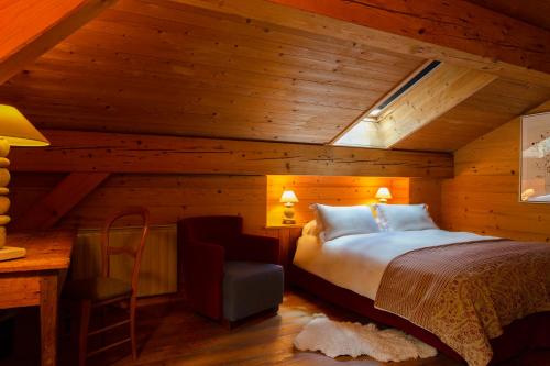 a bedroom with a bed and a desk and a chair at Hôtel La Ferme du Chozal, Chalet de tradition in Hauteluce