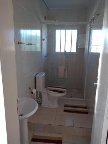 uma casa de banho com um WC, um lavatório e um chuveiro em Excelente apartamento por temporada na praia da barrinha em São Lourenço do Sul