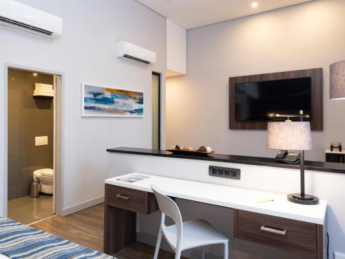 a room with a desk with a tv and a chair at aha Kathu Hotel in Kathu