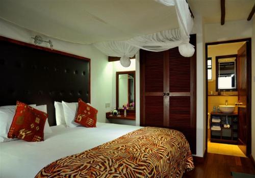 a bedroom with a large bed with red pillows at Mara River Lodge in Aitong