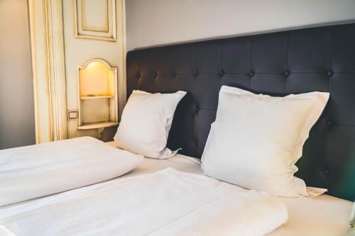 two white pillows on a bed with a black headboard at Hotel Spa et Restaurant Au Chasseur in Birkenwald