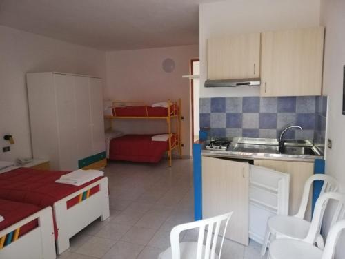 kuchnia ze zlewem oraz pokój z łóżkiem w obiekcie Villaggio Hotel Club Calanovellamare w mieście Piraino