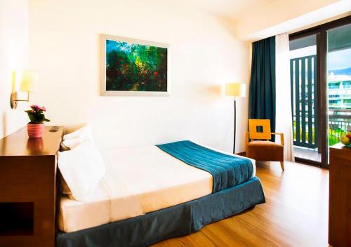 a hotel room with a bed and a desk and a window at Domotel Xenia Volos in Volos