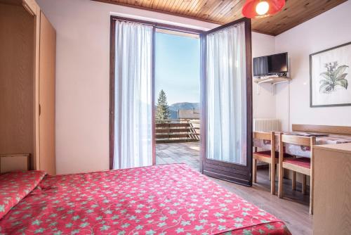フォルガリーアにあるAlaska Clubresidenceのベッドルーム1室(ベッド1台付)、スライド式ガラスドアが備わります。