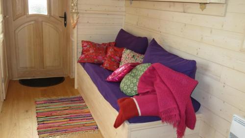 a bed with colorful pillows on it in a room at LE PETIT NID DANS LA ROULOTTE in Roscanvel