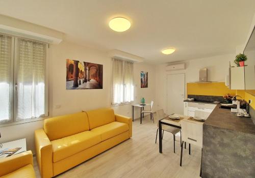 sala de estar con sofá amarillo y cocina en Casabetta "Felsina", en Bolonia