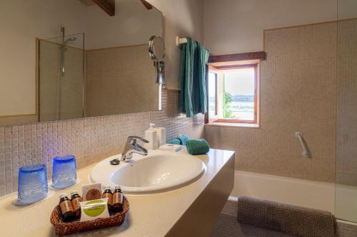 uma casa de banho com um lavatório, um espelho e uma banheira em Agroturismo sa Rota d' en Palerm em Lloret de Vistalegre