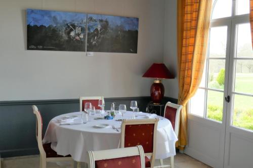 a dining room with a white table with chairs and a window at Hôtel Domaine de l'Orangerie in Bonnat