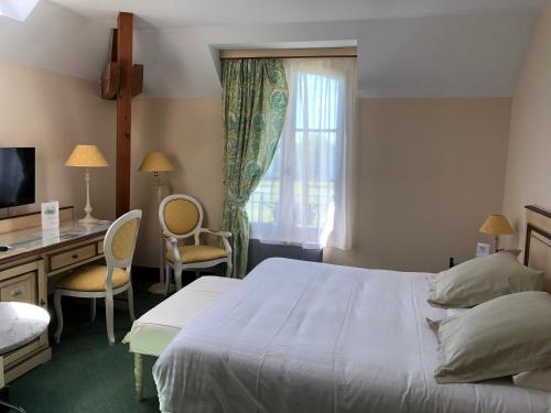 a bedroom with a bed and a desk and a window at Hôtel et Restaurant Domaine de l'Orangerie in Bonnat
