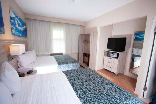 a hotel room with two beds and a television at Punta Borinquen Resort in Aguadilla