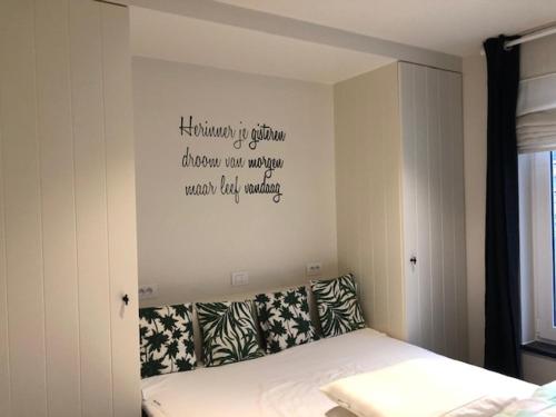 a bedroom with a bed with a sign on the wall at Merida in Knokke-Heist