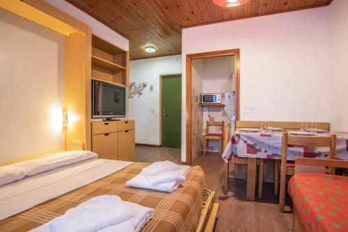 una stanza con due letti, un tavolo e una televisione di Alaska Clubresidence a Folgaria