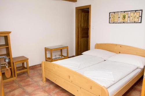 a bedroom with a wooden bed with white sheets at Penzion Baborákovi in Dětenice