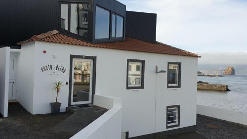 a white building with black windows and the water at Porto Velho Boutique Lodge in Madalena