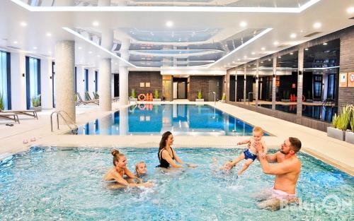 eine Familie im Pool eines Hotels in der Unterkunft Apartamenty BalticON Nadmorskie Tarasy in Kołobrzeg