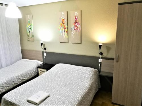 Habitación de hotel con 2 camas y 2 lámparas en Pension Santiago, en Burgos