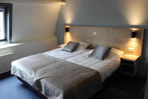 a bedroom with a large bed with two pillows at Hotel "De Klok" in Buren