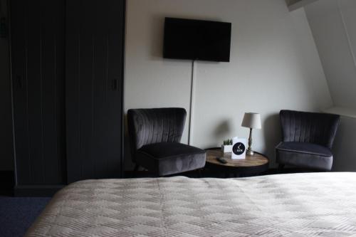 ein Hotelzimmer mit 2 Stühlen, einem Bett und einem TV in der Unterkunft Hotel "De Klok" in Buren