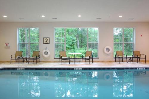 a pool with chairs and a table in a room with windows at Staybridge Suites North Brunswick by IHG in North Brunswick