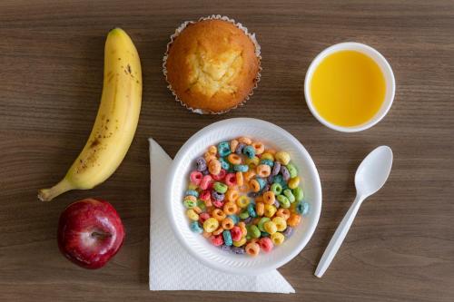 a table with a bowl of cereal and a cup of orange juice at Hotel Monreale Express International Drive Orlando in Orlando