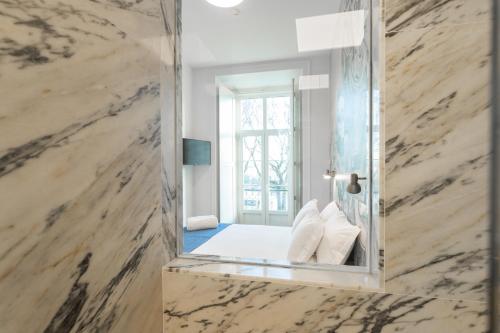 ein Schlafzimmer mit einem Spiegel in einem Zimmer mit einem Bett in der Unterkunft Bairro Alto Guesthouse in Lissabon