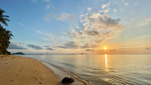 a sunset on the beach with footprints in the sand at Sean Sabai Home e Ristobar in Taling Ngam Beach